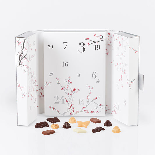 Summerbird signaturjulekalender i sølvdesign med 24 låger, hver med 2 økologiske chokolader i mørk og Amber-variant.
