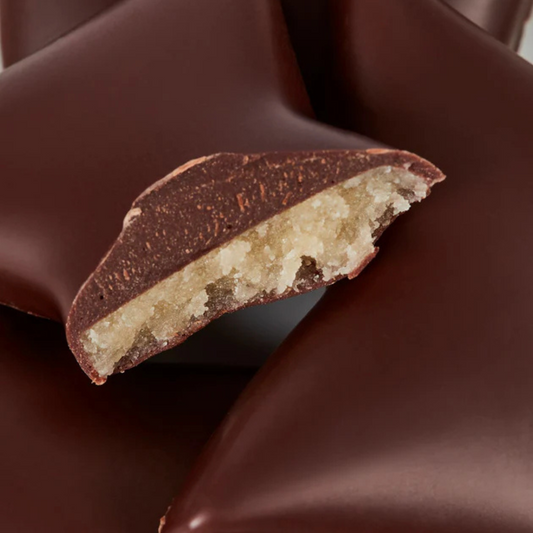 Nærbillede af overskåret fyldt chokolade med marcipanovertræk og mørk chokolade.